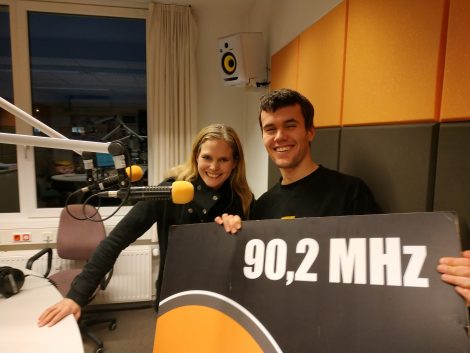 Die Sängerin Dota Kehr und Moderator Nils lächeln in die Kamera. Im Hintergrund das Sendestudio von LOHRO.