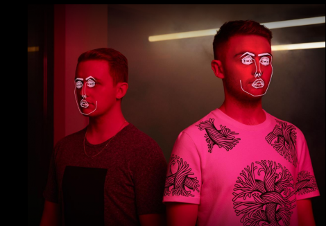 Guy und Howard Lawrence in pinkfarbigem Licht mit Illustrationen im Gesicht (Musikerduo Disclosure)