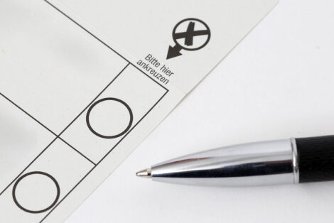 Anschnitt eines Wahlzettels mit Kugelschreiberspitze, die auf Ankreuzfeld zeigt