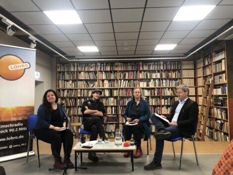 Antje Benda. Aljoscha Hartmann, Frauke Lietz und Bert Lingnau auf Stühlen nebeneinander sitzend vor Bücherregal